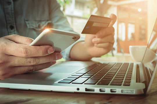 Man's hands holding smartphone and using credit card for online shopping.