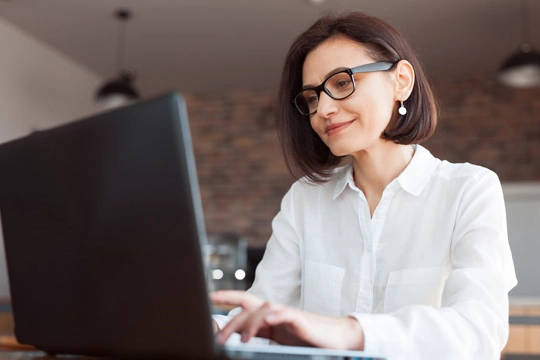 Eine Frau mit Brille sitzt vor ihrem Laptop