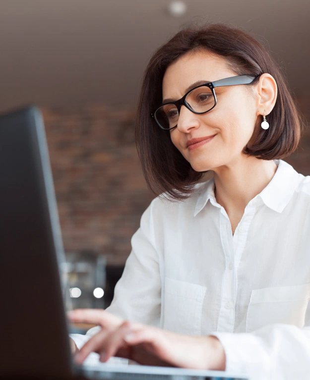 Eine Frau mit Brille sitzt vor ihrem Laptop