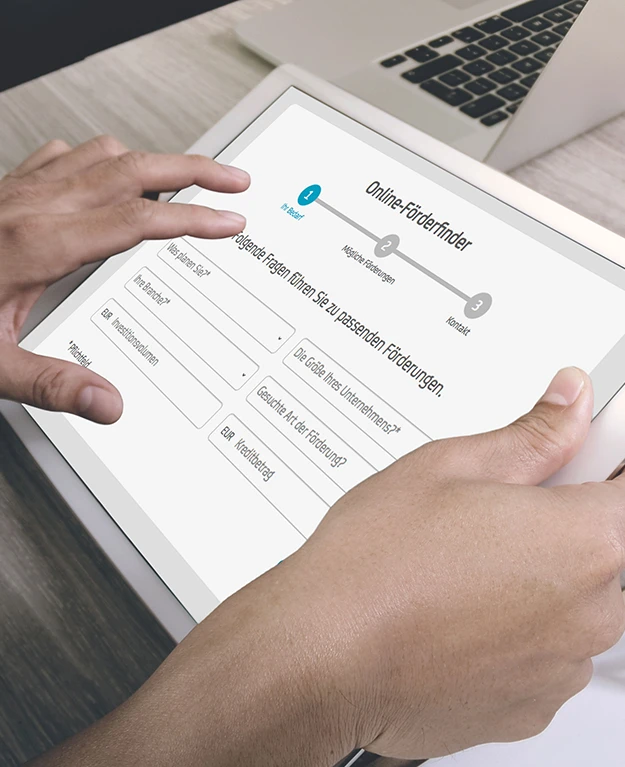jemand hält ein Tablet mit dem Online-Förderfinder darauf in den Händen
