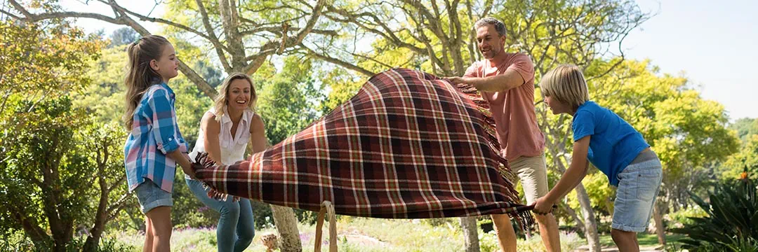 eine Familie breitet eine Picknickdecke aus