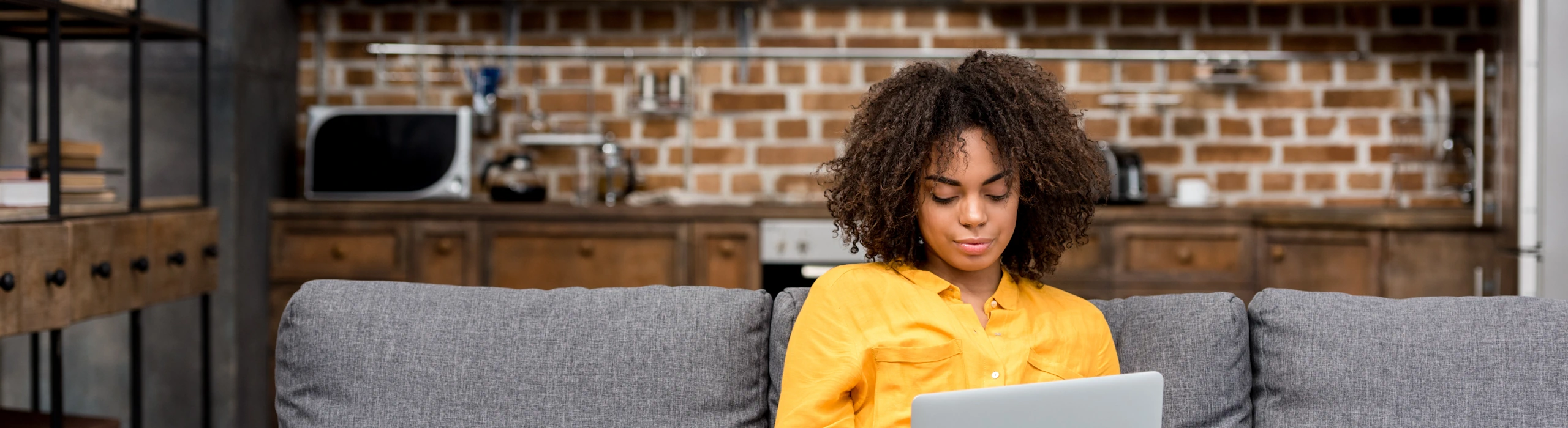 Eine Frau sitzt mit dem Laptop auf der Couch