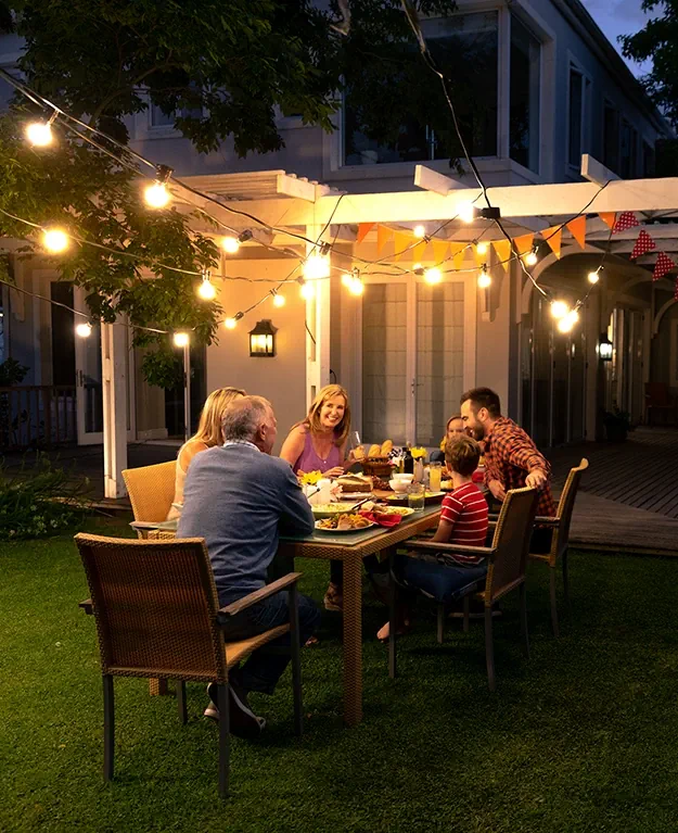 Eine Familie sitzt im Garten ihres Hauses