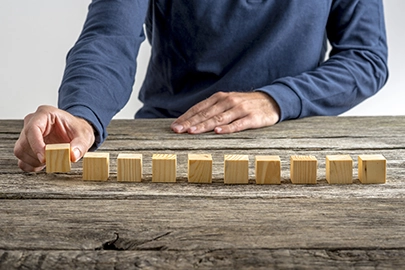 Ein Mann stellt Holzwürfel nebeneinander in eine Reihe