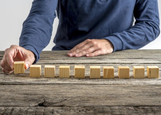 ein Mann stellt Holzwürfel in einer Reihe auf