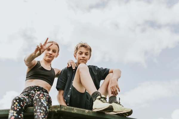 ein Mädchen und ein Bursche sitzen auf einer Mauer