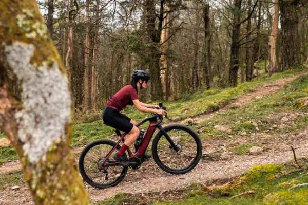 Eine Frau fährt mit ihrem E-Bike im Wald