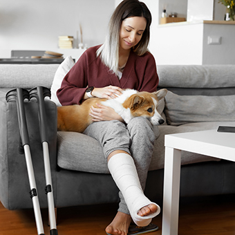 Eine Frau mit einem gebrochenen Bein hat einen Hund am Schoß