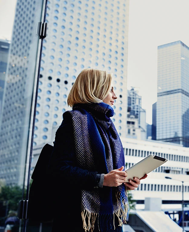 Eine Frau mit dem Tablet in der Hand zwischen Hochhäusern