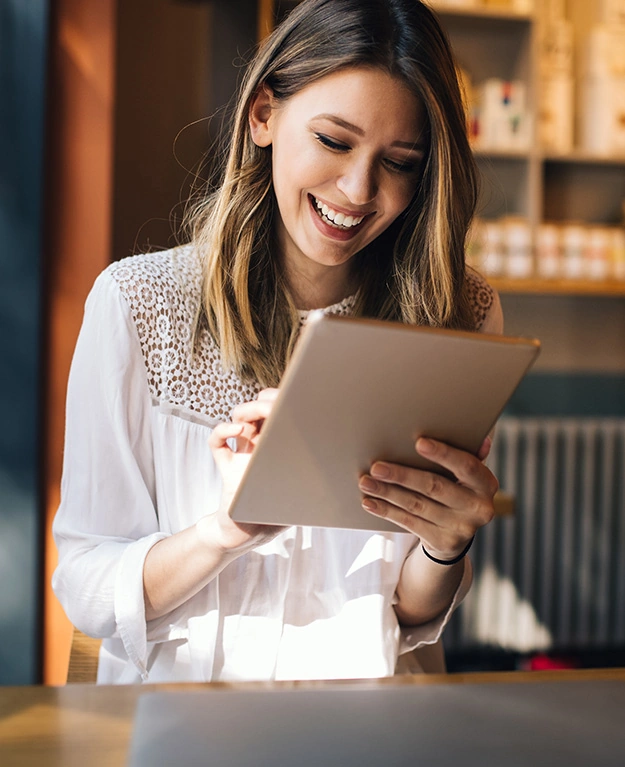 Eine junge Frau schaut lachend auf ihr Tablet