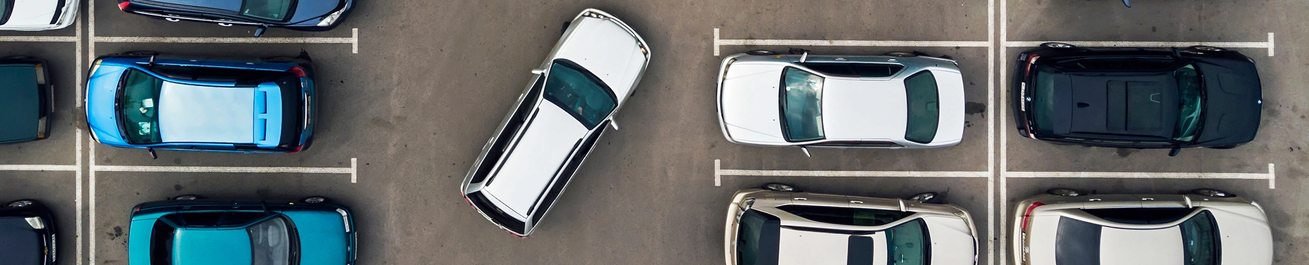 Mehrere Autos nebeneinander auf einem Parkplatz von oben fotografiert