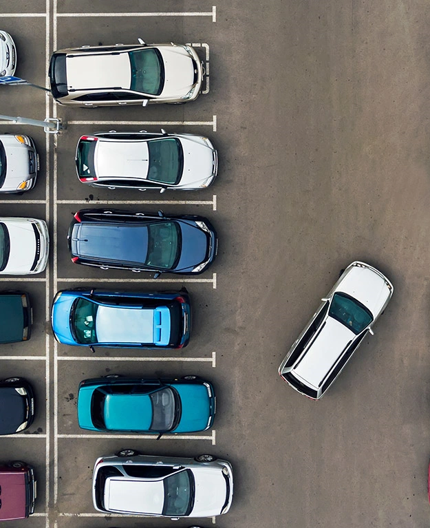 Mehrere Autos nebeneinander auf einem Parkplatz von oben fotografiert