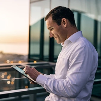 Mann steht am Balkon mit Tablet in der Hand