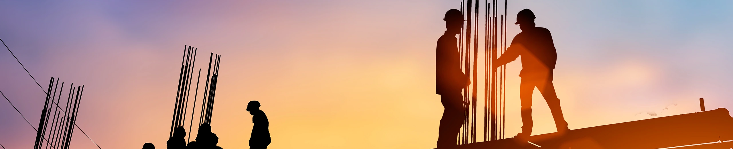 Bauarbeiter stehen auf einer Baustelle bei Sonnenuntergang