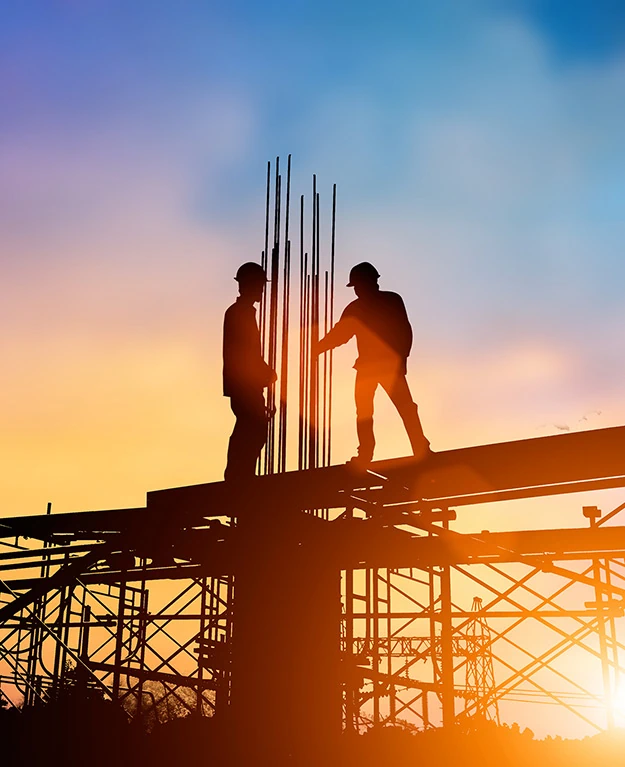 Bauarbeiter stehen auf einer Baustelle bei Sonnenuntergang