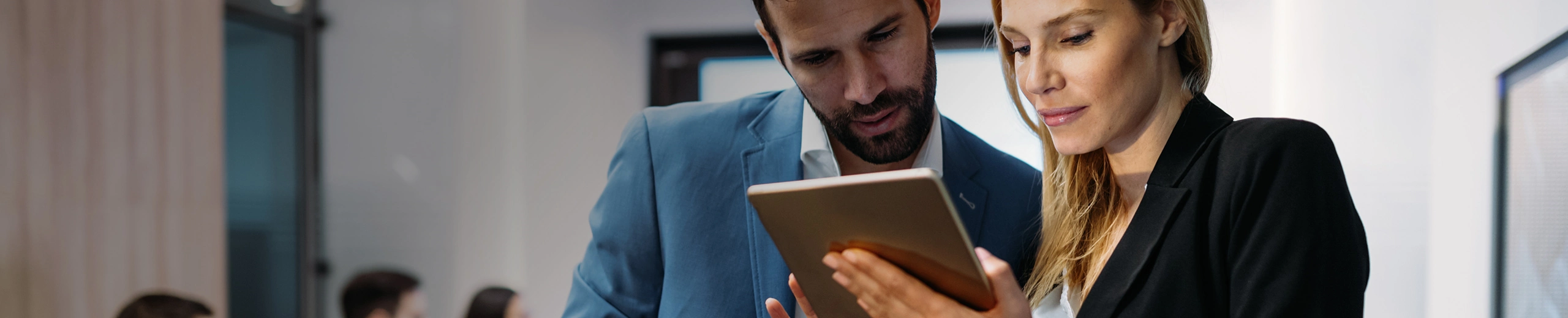 Eine Frau und ein Mann in Anzug halten ein Tablet in der Hand