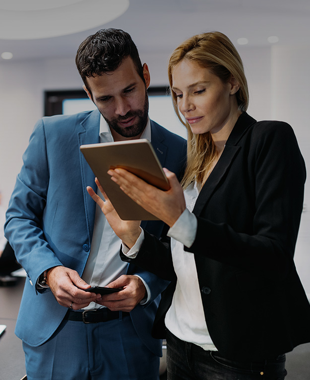 a woman and a man in business clothings looking on a tablet