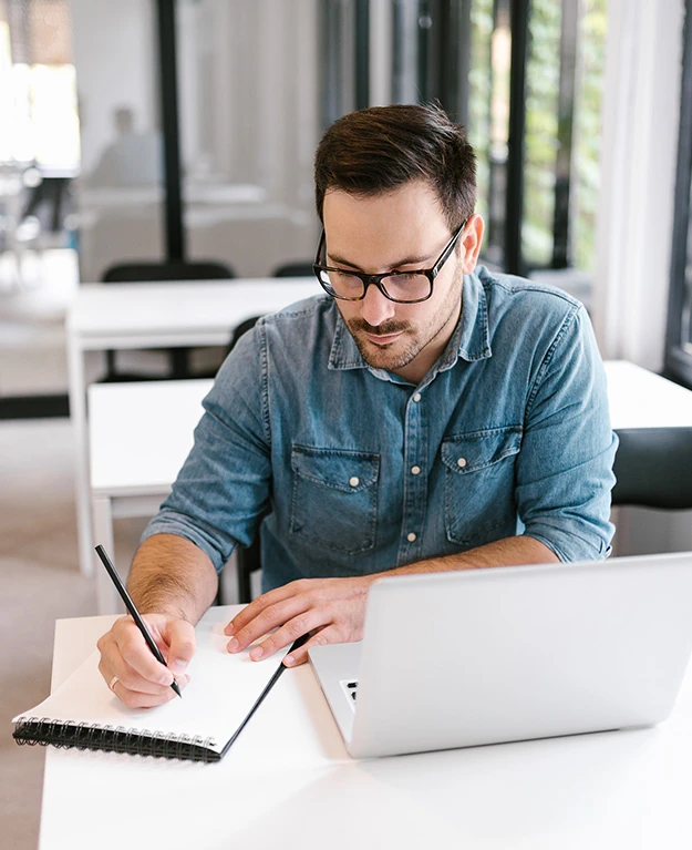 man writing on paper on his desk