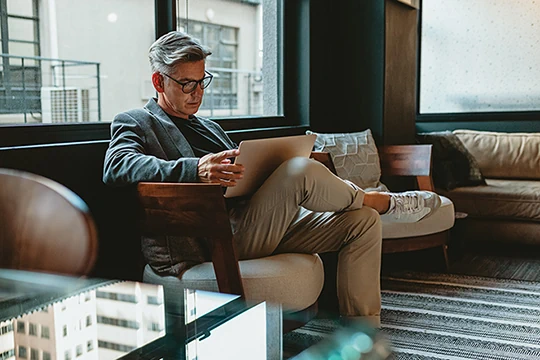 Ein Mann sitzt auf dem Sofa vor dem Laptop