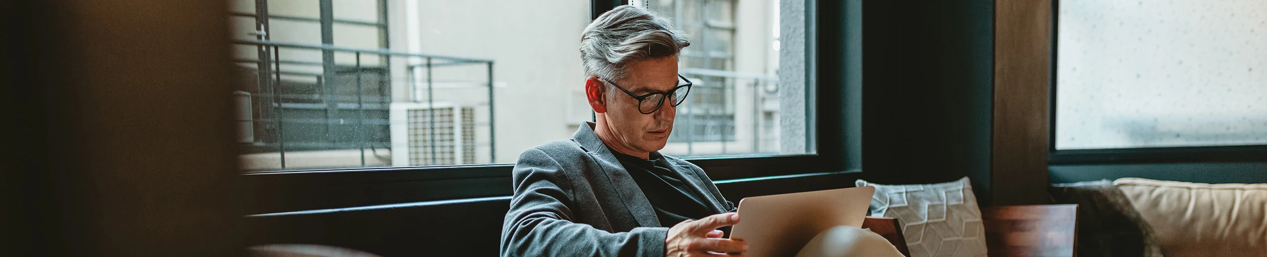 Ein Mann sitzt mit seinem Laptop auf der Couch