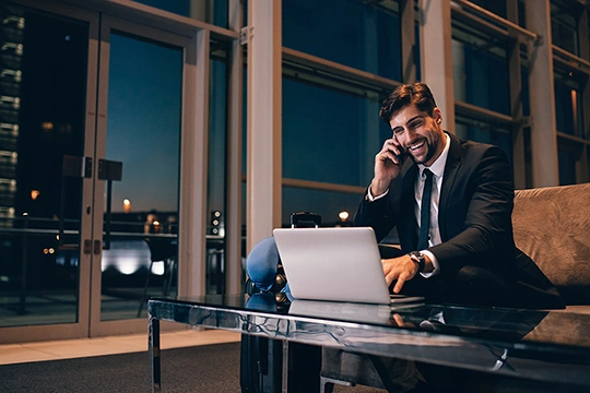 Mann im Anzug sitzt vor einem Glasschreibtisch und Laptop