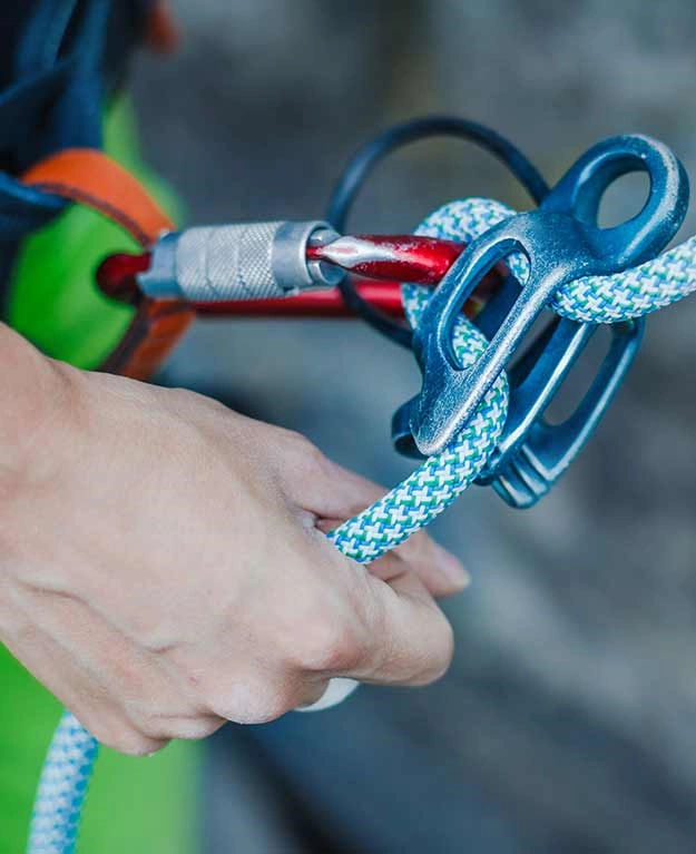 Ein Kletterer befestigt einen Karabiner an seiner Ausrüstung 