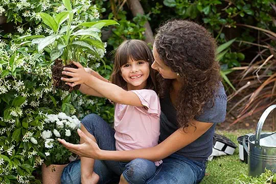 Eine Frau mit einem Mädchen beim Einpflanzen im Garten