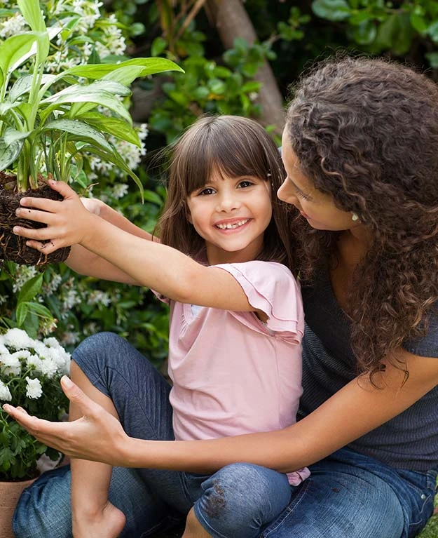 Frau mit Mädchen beim Einpflanzen im Garten