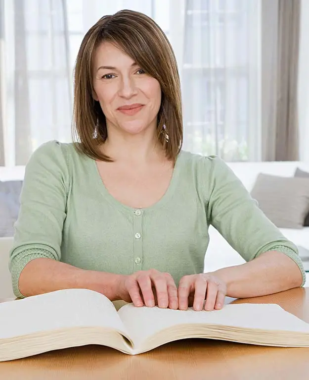 Frau liest ein Buch in Brailleschrift