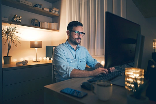 An Mann sitzt hinter seinem Computerbildschirm