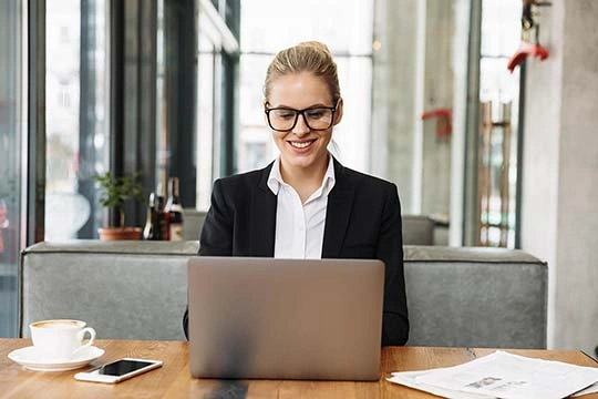 Eine Frau sitzt in einem Kaffeehaus und arbeitet auf ihrem Laptop