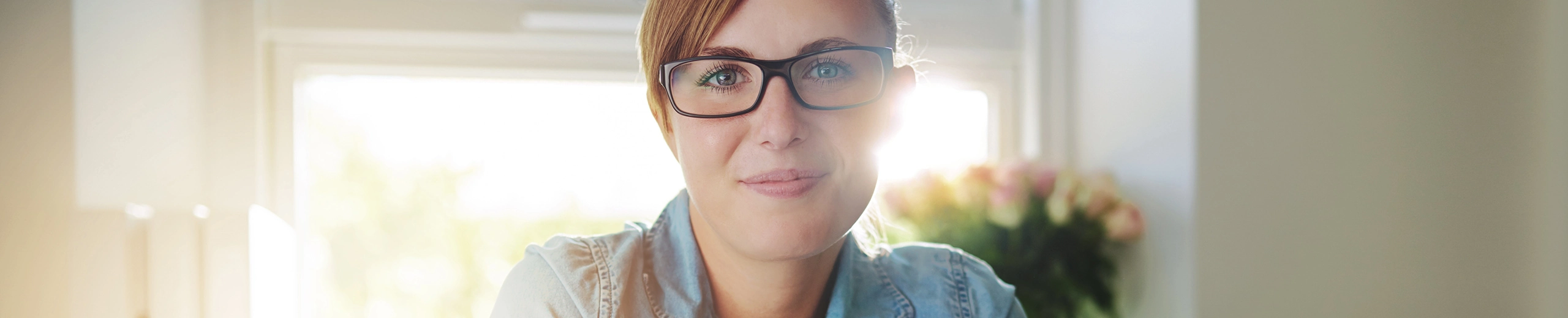 Eine junge Frau mit Jeansbluse sitzt an einem Schreibtisch