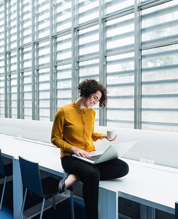 Woman with yellow blouse looks into her laptop