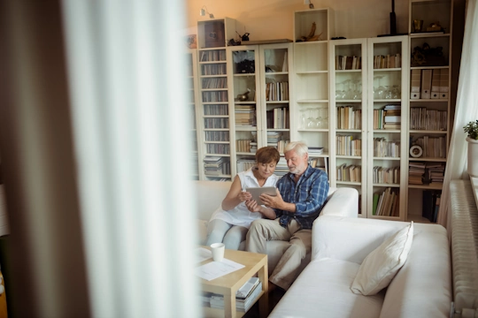 ein älteres Paar sitzt auf der Couch mit einem Tablet in der Hand