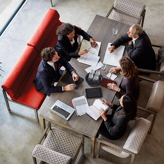 5 Personen sitzen an einem Besprechungstisch, Blick von oben