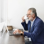 Mann mit Kaffeetasse und Laptop