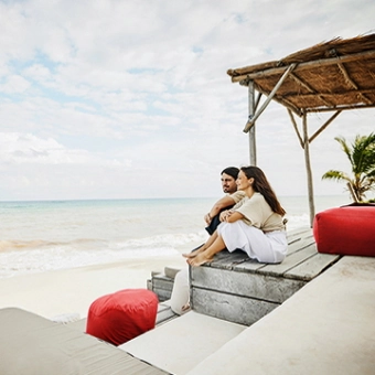 A couple sits on a terrace and looks at the sea