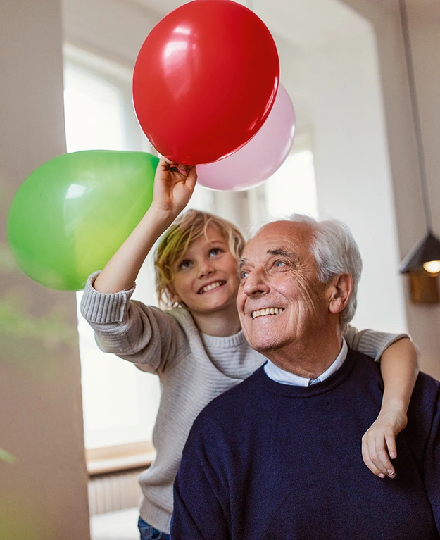 Ein Großvater mit seinem Enkelkind mit Luftballons