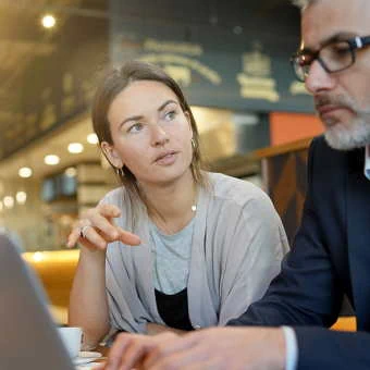 Eine Frau schaut einen Mann an, der ihr etwas auf dem Laptop zeigt