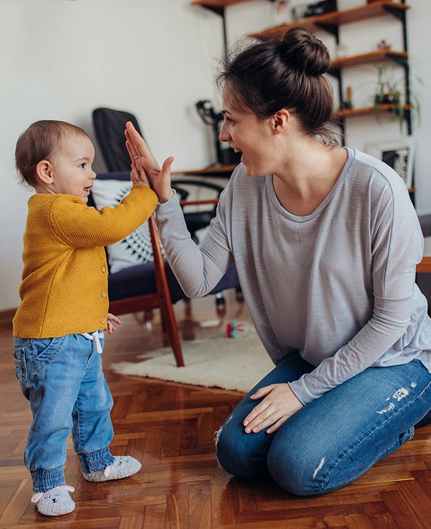 Eine Mutter mit ihrem kleinen Kind, sie klatschen sich in die Hände