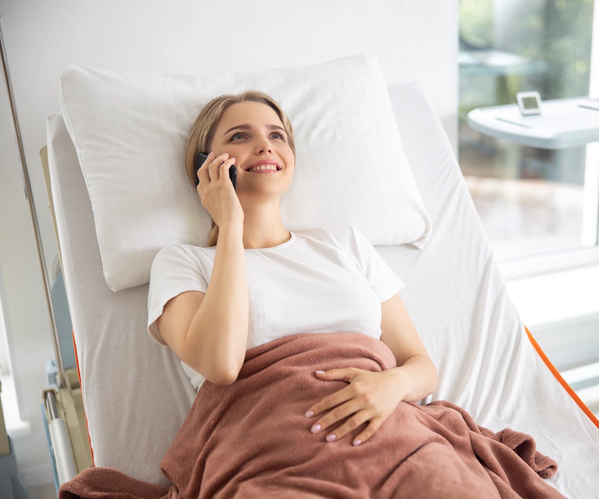 Eine Frau liegt im Krankenhaus und telefoniert