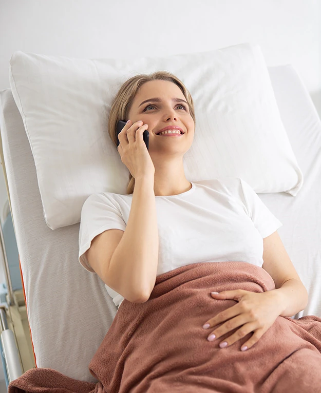 Eine Frau liegt im Krankenhaus und telefoniert