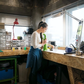 Mädchen mit Roboterarm in der Hand in einer Werkstatt