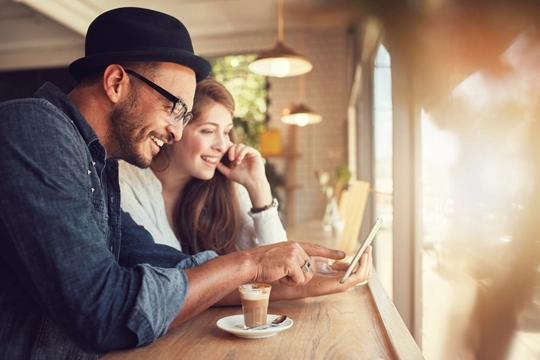 Eine Frau und ein Mann sitzen nebeneinander vor dem Handy