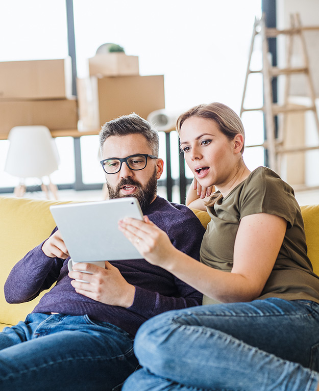 Eine Frau und ein Mann schauen erstaunt auf ihr Tablet