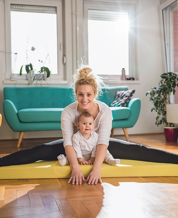 Eine Frau sitzt mit ihrem Kind auf einer Yogamatte