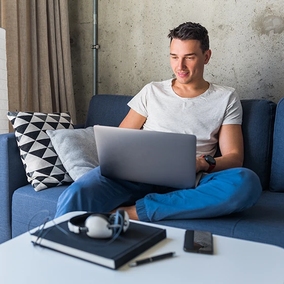 Ein Mann sitzt mit seinem Laptop auf der Couch