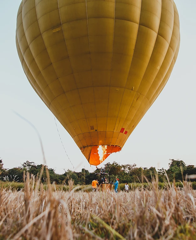 ein abhebender Heißluftballon in einem Feld