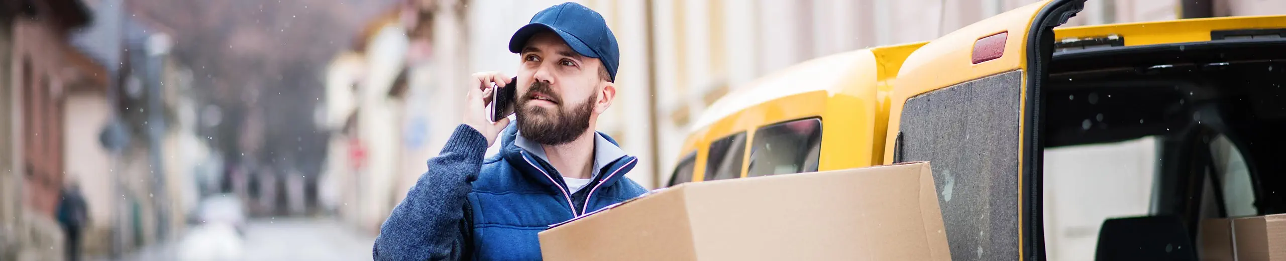 Mann telefoniert und liefert ein Paket aus