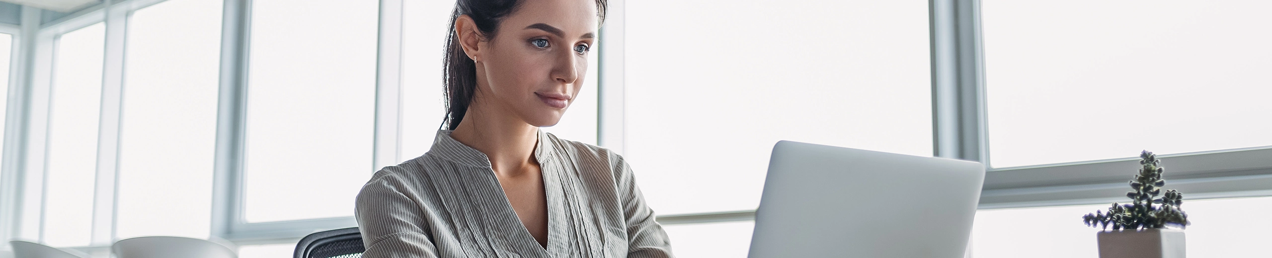 Eine Junge Frau sitzt im Büro vor ihrem Laptop